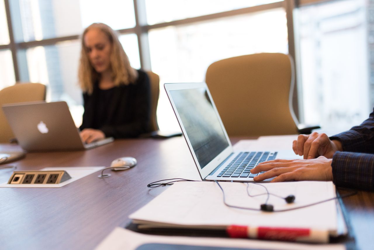 Services Colleagues collaborating in a bright, modern office setting, focused on laptop work.