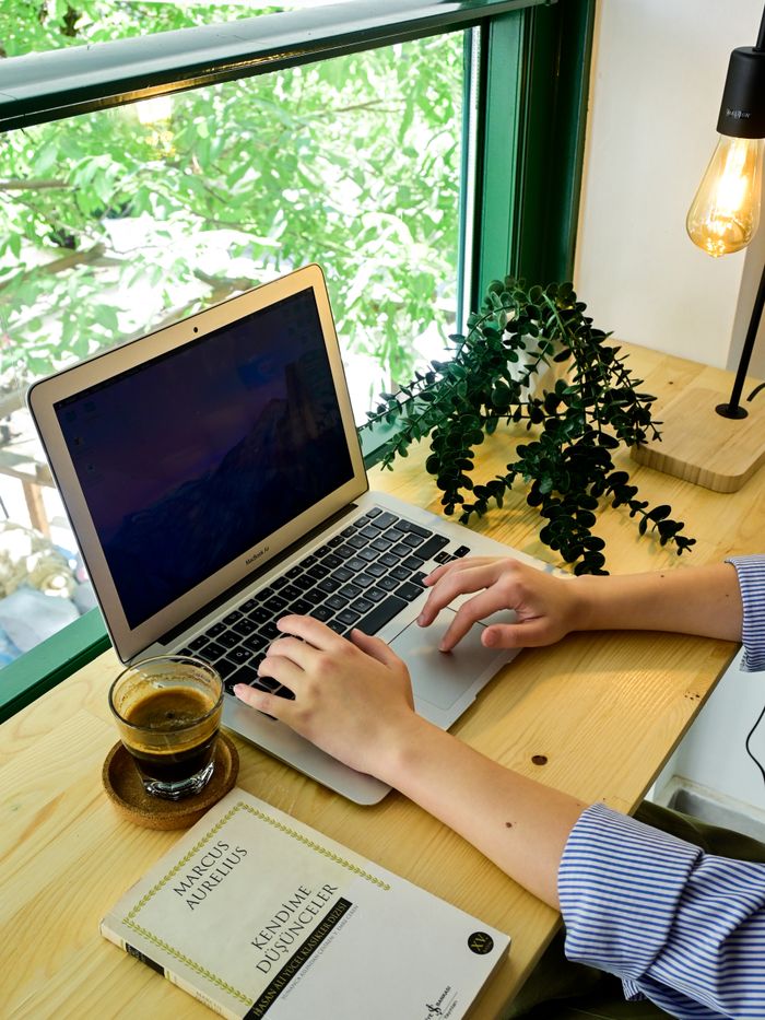 Services Tranquil workspace with laptop, coffee, and plant by a sunlit window.
