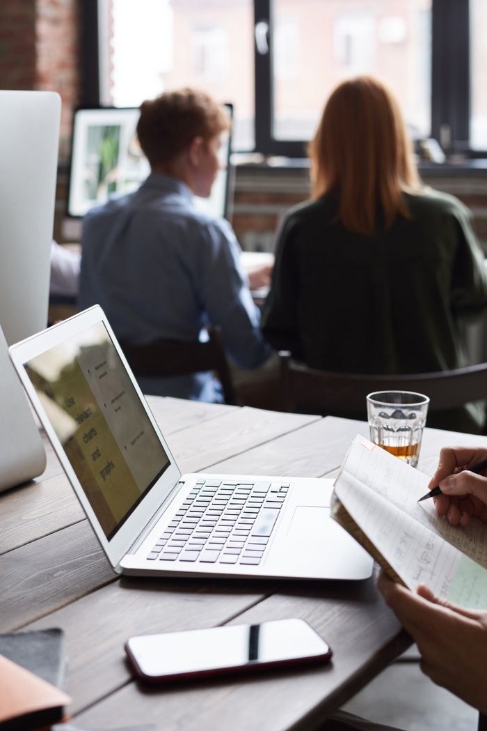 About Group of adults working indoors, collaborating with technology, and taking notes for a business project.